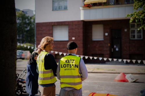 Zwei Ordner tragen Warnwesten mit dem Aufdruck "Kiez Lots*in"