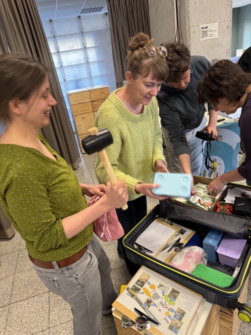 Der Inhalt des Lernkoffers wird inspiziert. Es werden Bücher, Mikroskope und ein Gummihammer herausgenommen